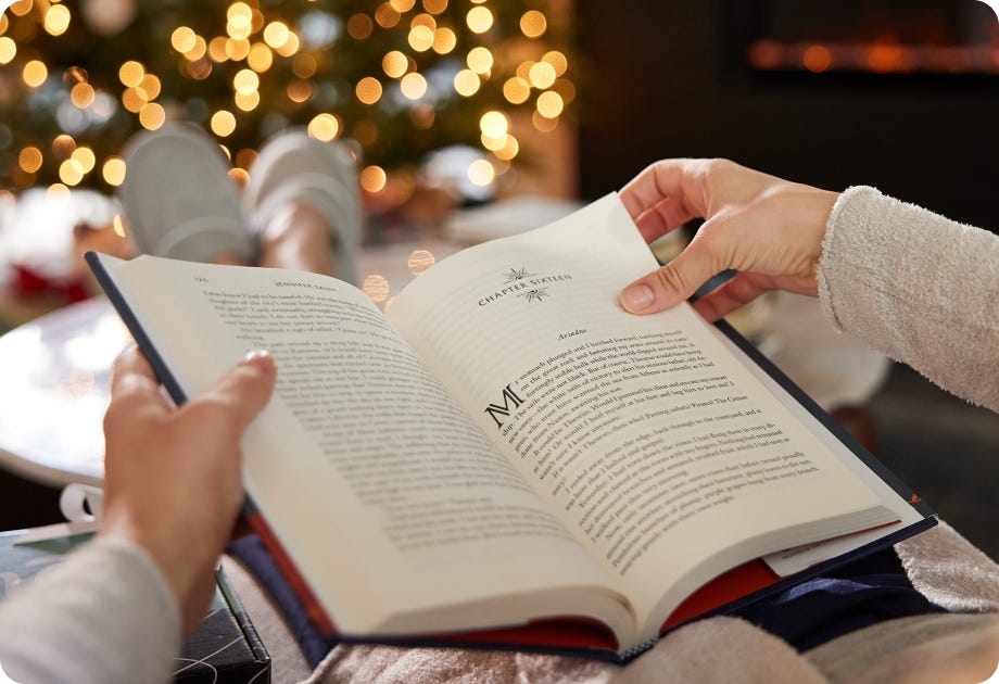 Woman reading a book in front of the christmas tree.